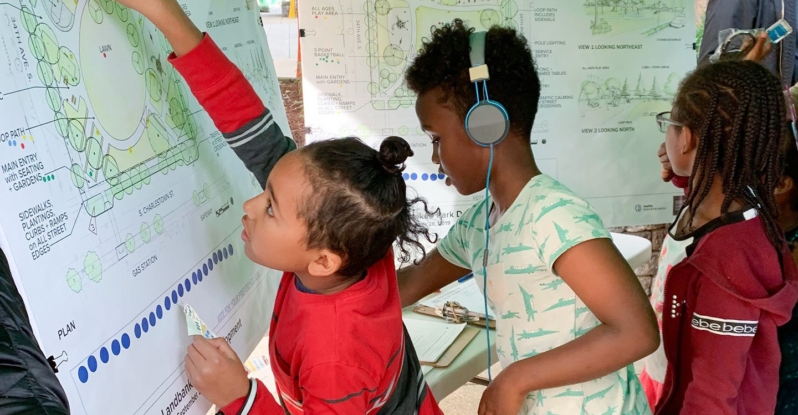 Three older kids interacting with poster plans of a new park
